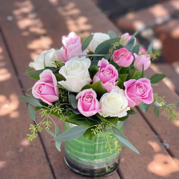 Pink and white roses arranged in a glass vase