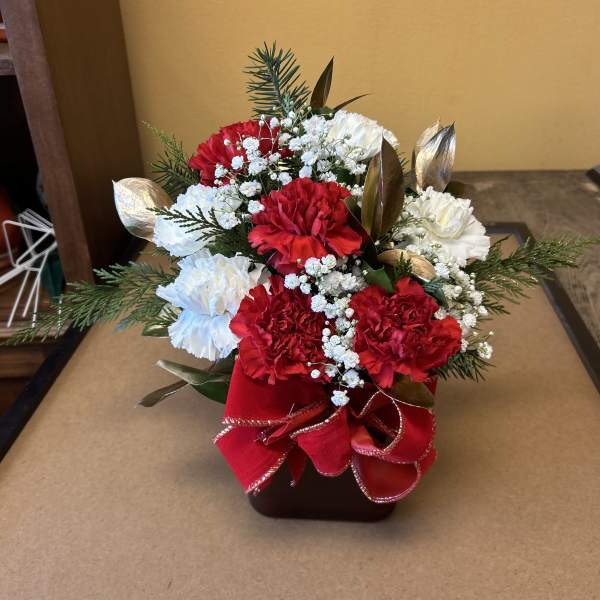 Red and white carnation arrangement in a square vase with a red ribbon