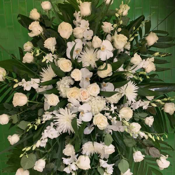 Large white floral spray with roses and orchids against green tiles