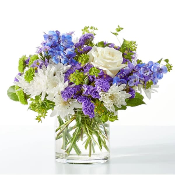 Bouquet of blue, purple, and white flowers in a clear glass vase