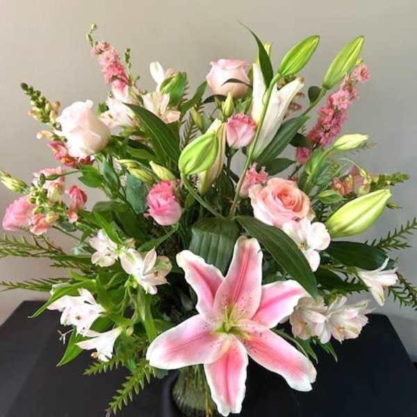 Pink lilies and roses arranged in a glass vase