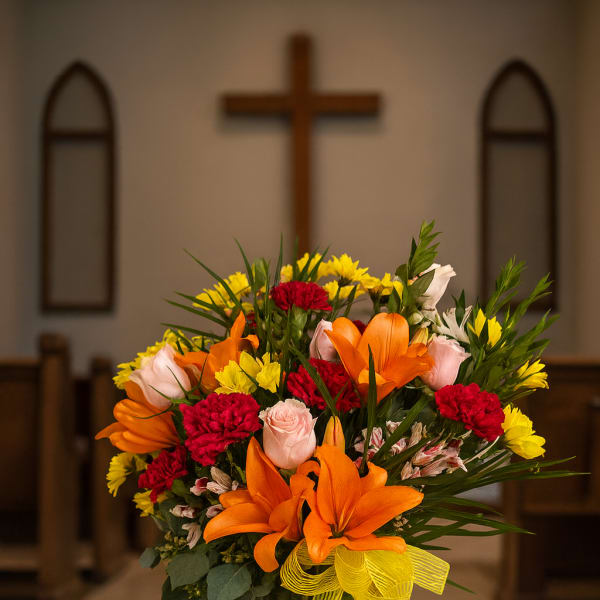 Colorful flower arrangement in a tall glass vase with a yellow ribbon