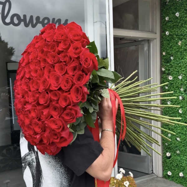 Large bouquet of red roses with long stems and a red ribbon