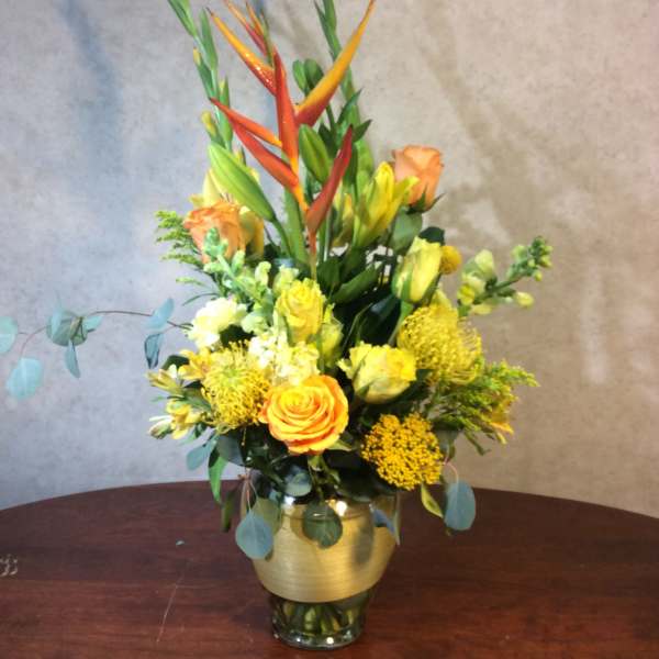 Tall mixed bouquet in a glass vase with orange and yellow flowers