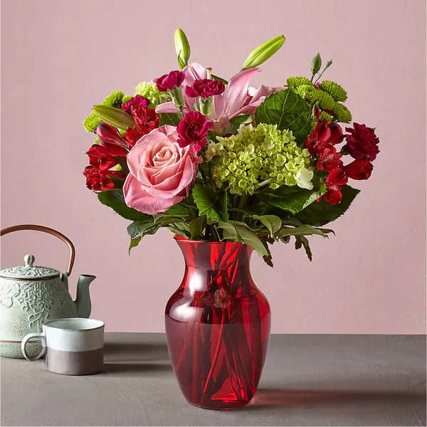Pink and red mixed bouquet in a red glass vase