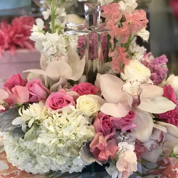 Pink and white floral arrangement with a clear cross centerpiece