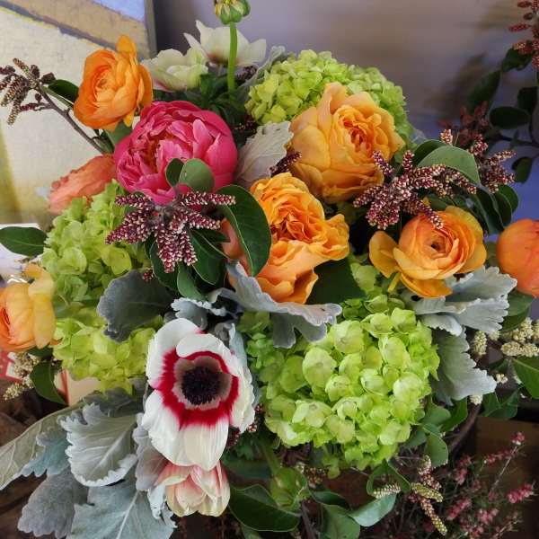 Bouquet of orange and pink flowers with green hydrangeas and a white anemone