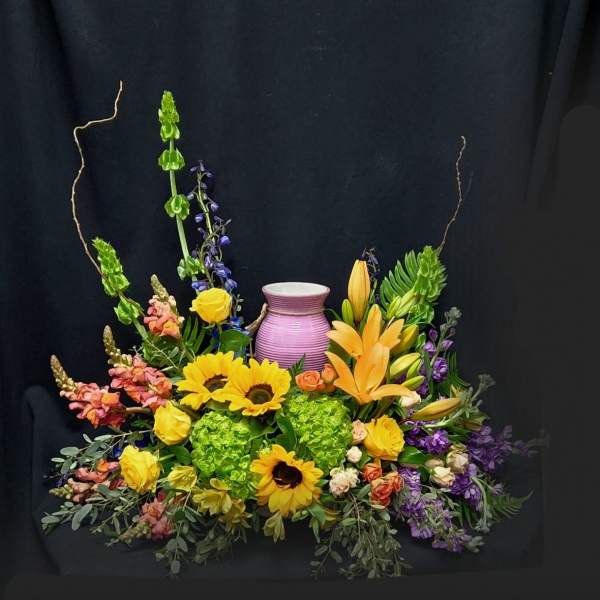 Colorful floral arrangement with sunflowers, lilies, and a purple vase