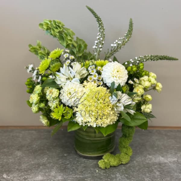 Green and white floral arrangement in a glass vase