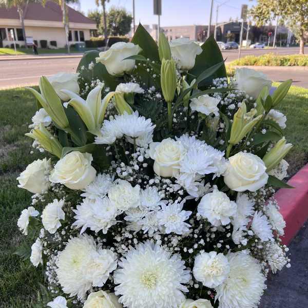 Large white floral standing spray with roses, lilies, and chrysanthemums