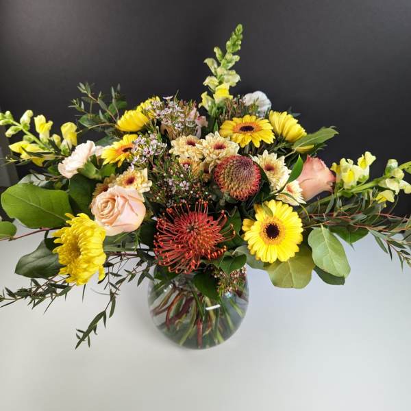 Mixed yellow and peach flowers in a glass vase