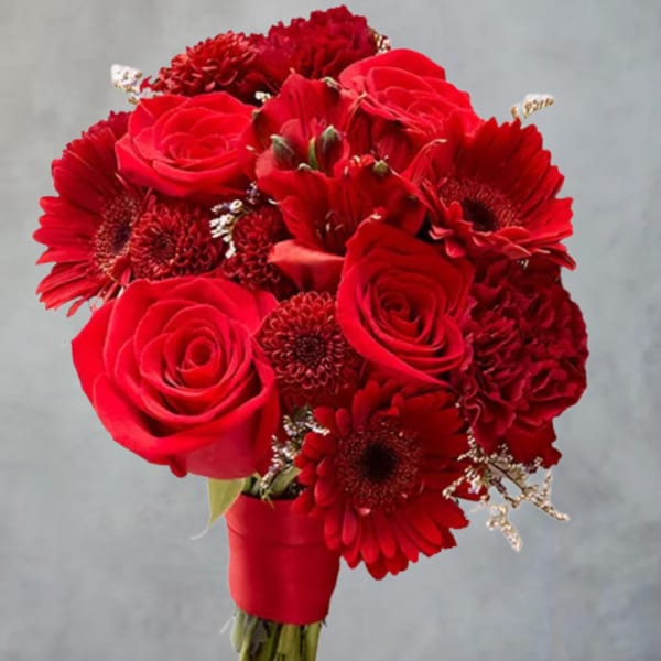 Red rose and gerbera daisy bouquet in a red wrap on a stand