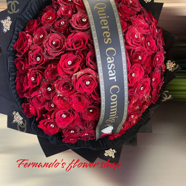 Large round bouquet of red roses with rhinestones, black wrapping, and a printed proposal ribbon.
