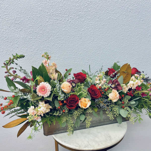 Long floral centerpiece with red and peach roses in a rectangular container