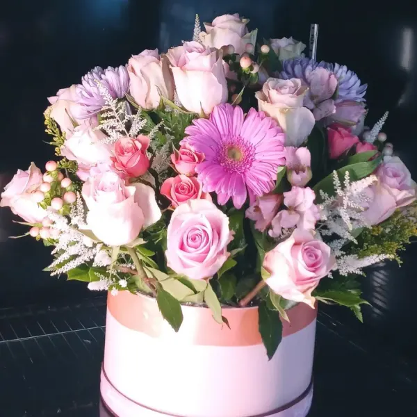 Pink and lavender roses with a pink gerbera daisy in a round box