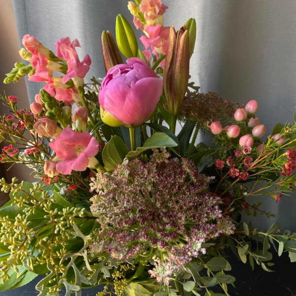Mixed bouquet with pink peonies, lilies, and snapdragons in a glass vase