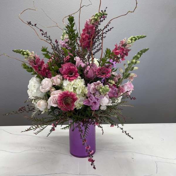 Pink and white floral arrangement in a purple vase