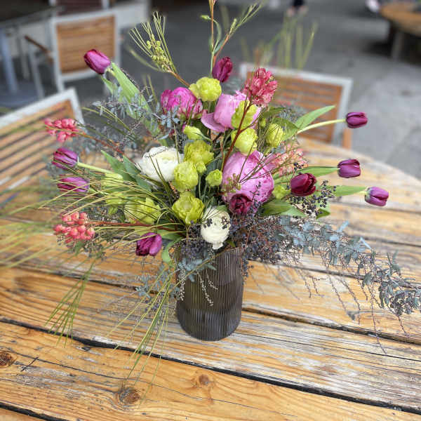 Mixed bouquet of pink, white, and lime flowers in a dark vase