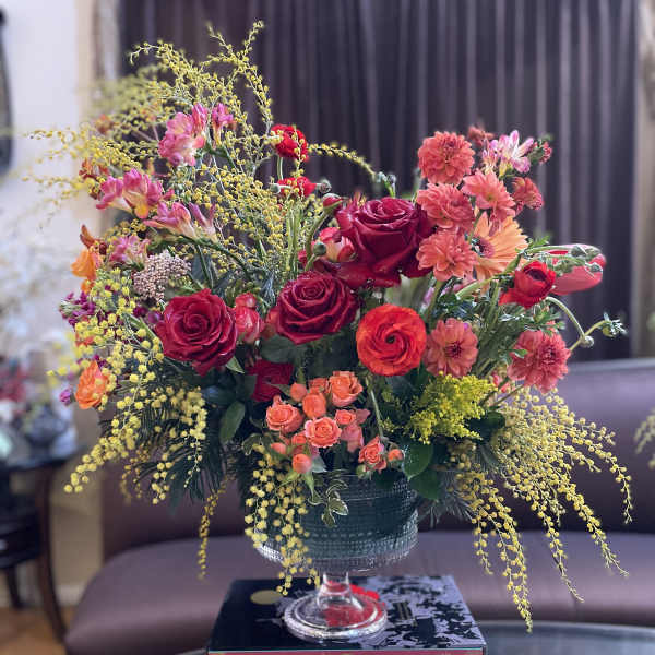 Mixed bouquet of red and pink flowers in a glass compote vase