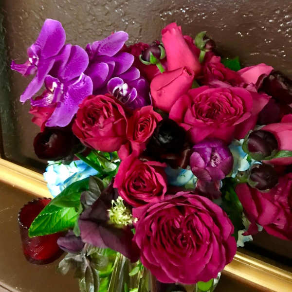 Bouquet of pink roses and purple orchids in a glass vase