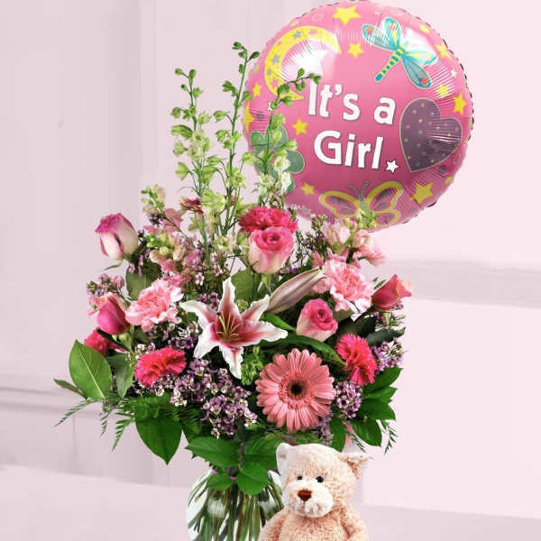 Pink flower arrangement in a glass vase with It's a Girl balloon and teddy bear