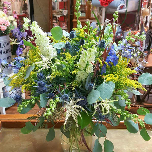 Mixed bouquet in a clear glass vase with blue, white, and yellow flowers