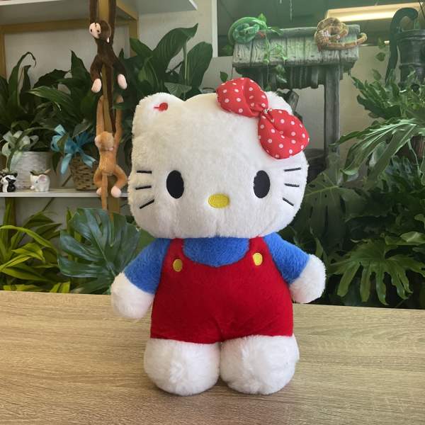 Hello Kitty plush toy in red overalls with a polka-dot bow