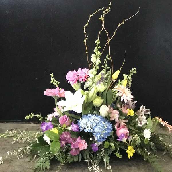 Large mixed floral arrangement with pink, white, blue, and yellow blooms