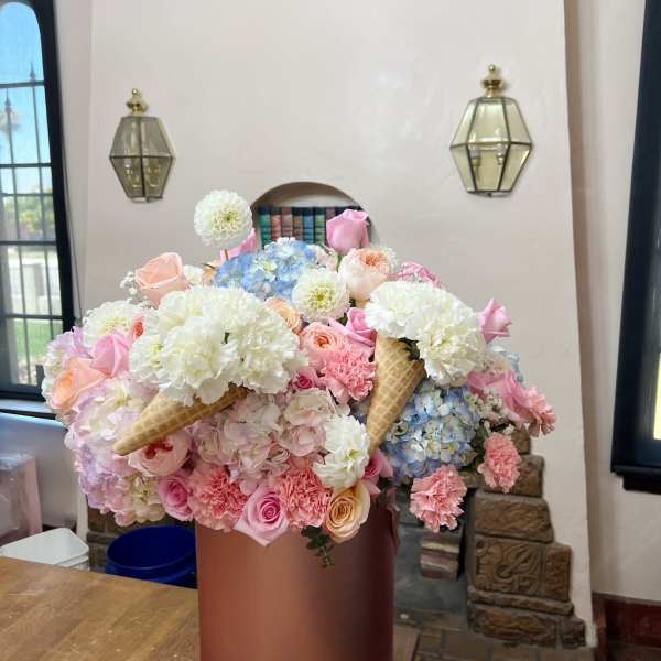 Large pastel flower arrangement in a round pink box with ice cream cone accents