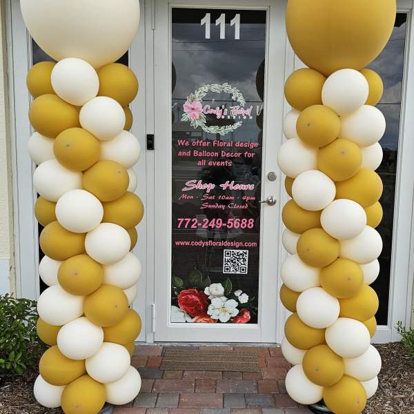 Yellow and white balloon columns flank a storefront door.