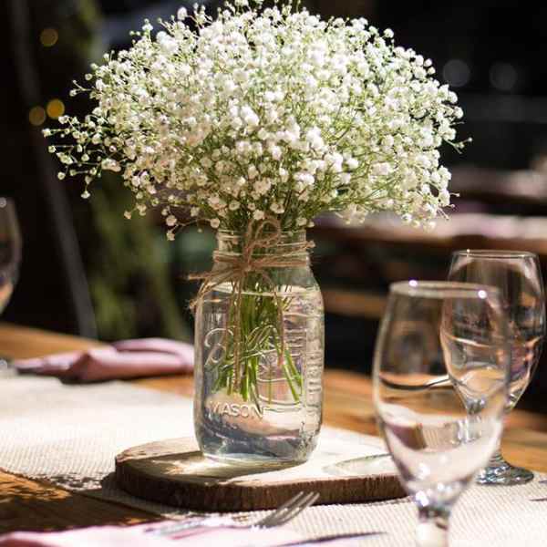 White baby's breath in a glass jar centerpiece on a table