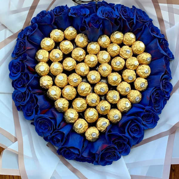Heart-shaped bouquet of blue roses surrounding gold-wrapped chocolates