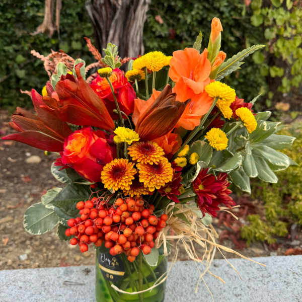 Orange and red bouquet in a glass vase with yellow blooms
