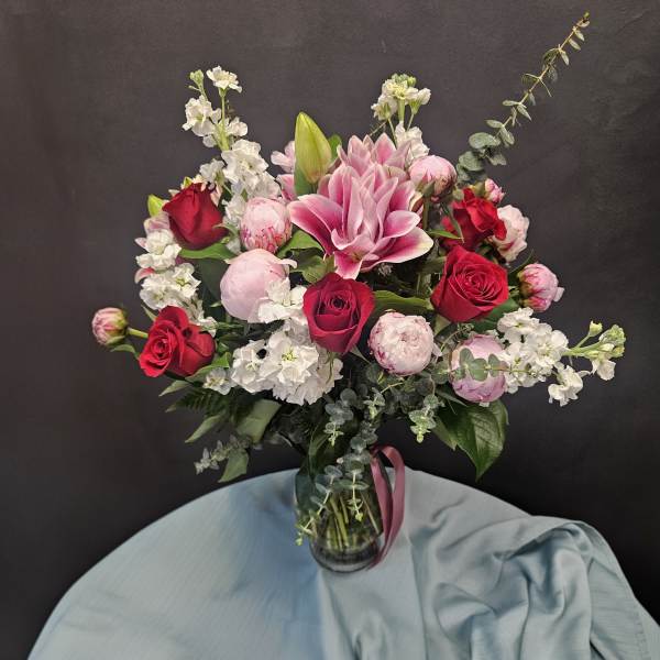 Pink and red roses with lilies in a glass vase