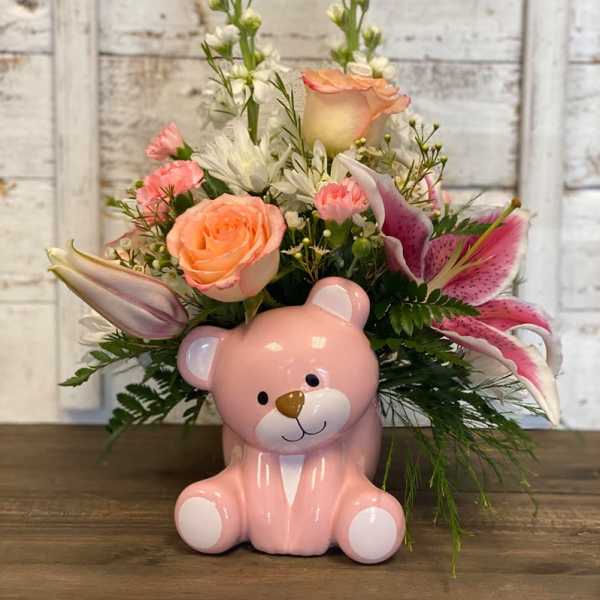 Pink teddy bear vase holding a mixed bouquet of roses and lilies