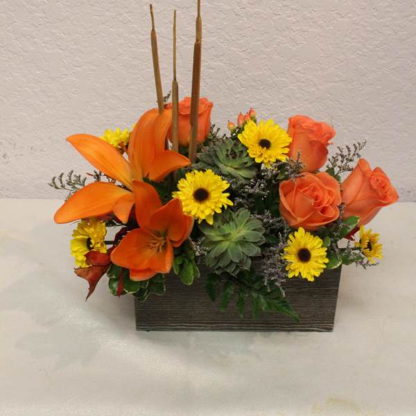 Orange roses and yellow daisies in a rectangular wooden container