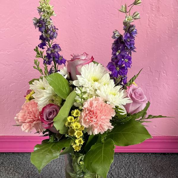 Mixed bouquet of pink, white, and purple flowers in a glass vase