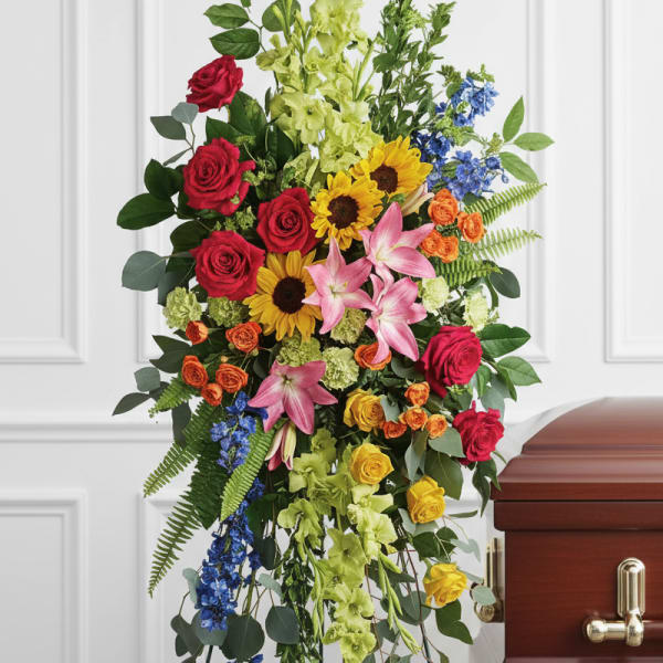 Tall standing floral spray with red roses, lilies, and blue accents