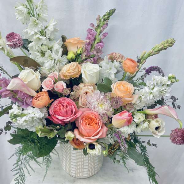 Mixed bouquet of roses, calla lilies, and snapdragons in a white vase