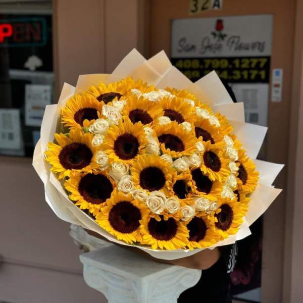 Bouquet of sunflowers and white roses wrapped in white paper