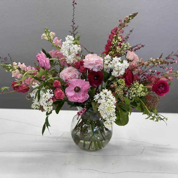 Pink and white mixed flower arrangement in a round glass vase