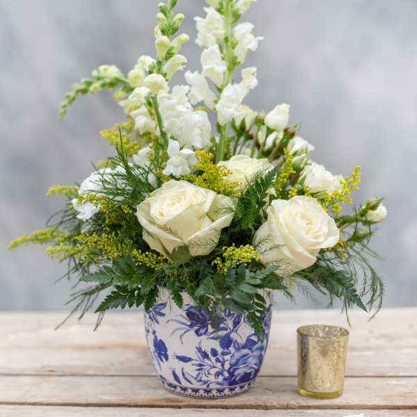 White roses and snapdragons in a blue-and-white ceramic vase