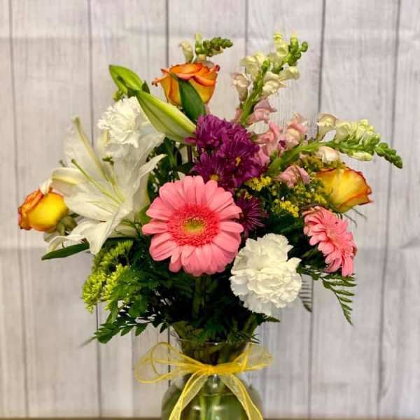 Mixed bouquet of pink, white, purple, and orange flowers in a glass vase