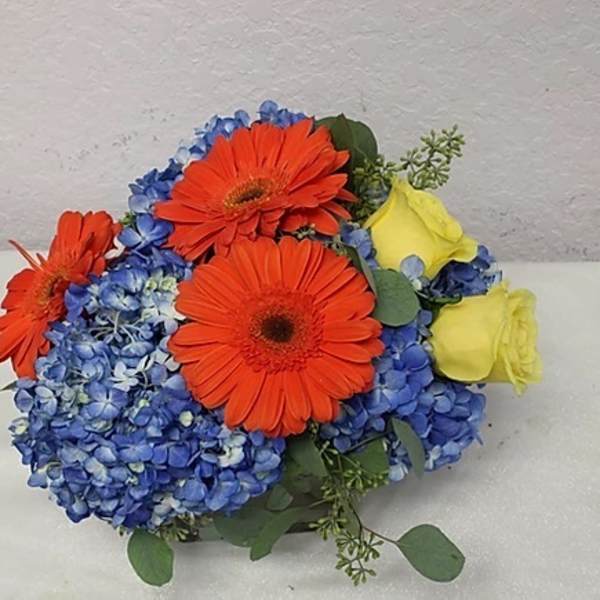 Bouquet of orange gerbera daisies, blue hydrangeas, and yellow roses