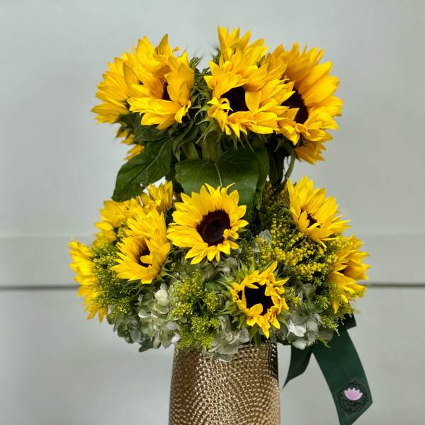 Sunflower arrangement in a gold textured vase with a green ribbon