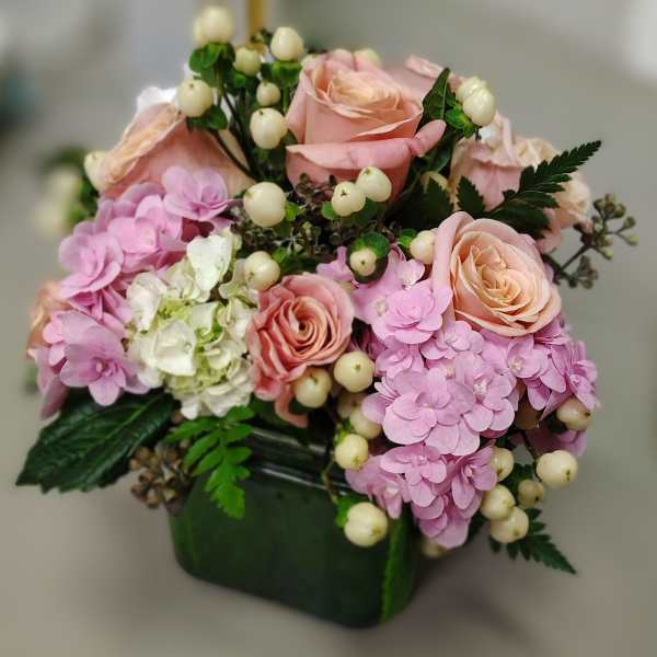 Pink roses and hydrangeas arranged in a dark green vase
