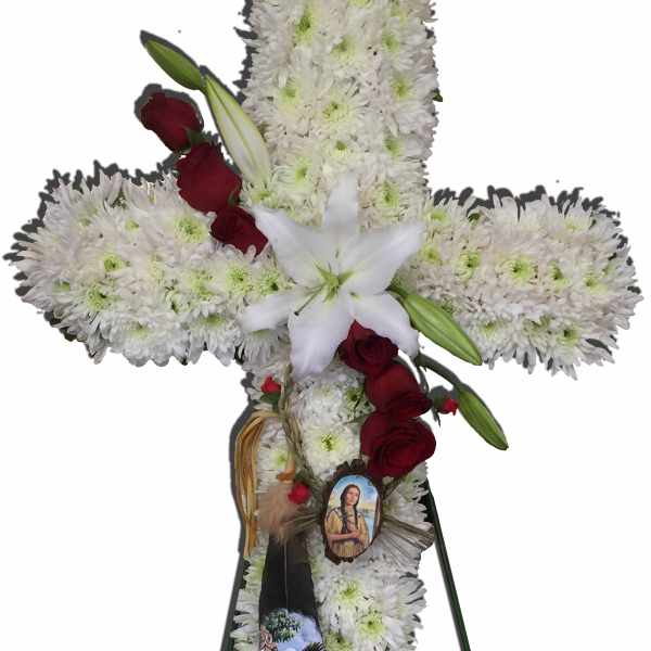White floral cross on a stand with red roses and a white lily