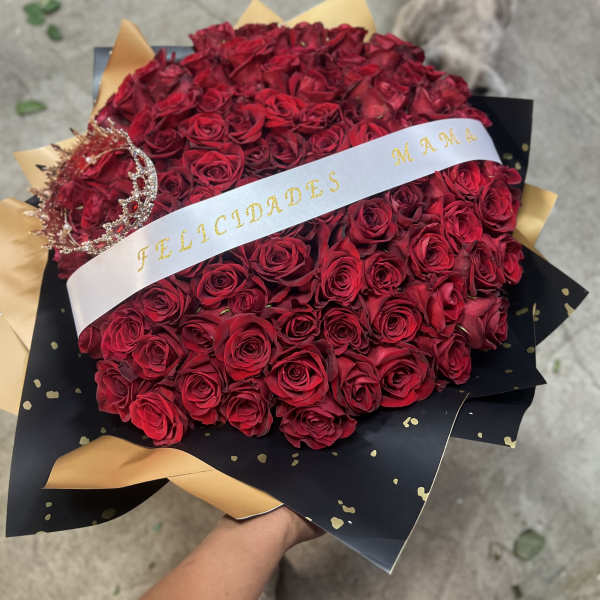Large bouquet of red roses wrapped in black and gold paper with a white ribbon