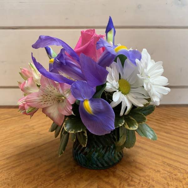 Small bouquet of purple, pink, and white flowers in a glass vase