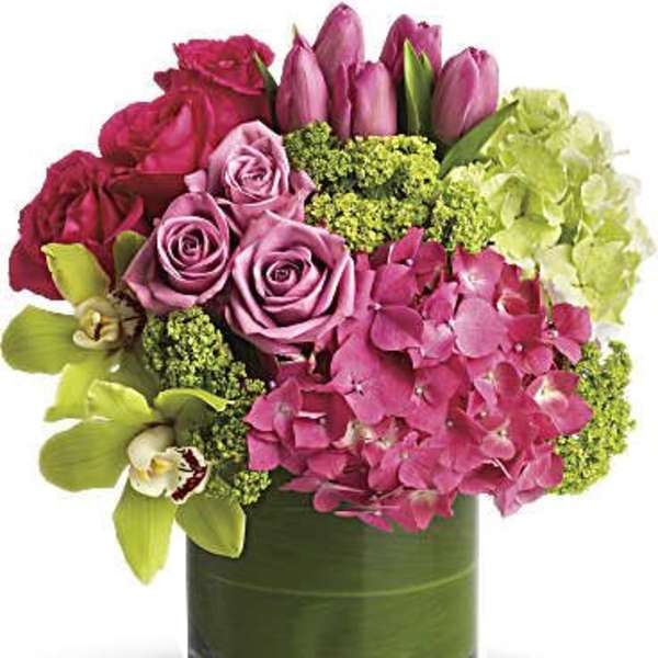 Pink roses, tulips, hydrangea, and orchids in a glass vase